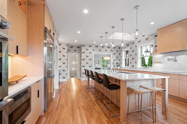 343 Washington Ave, Wilmette, IL 60091 - kitchen with light brown cabinets, a breakfast bar, modern cabinets, light countertops, and light wood-style flooring