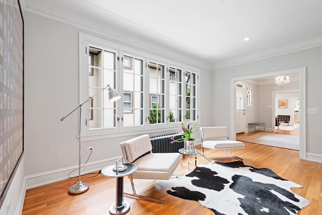 343 Washington Ave, Wilmette, IL 60091 - living area featuring crown molding, radiator heating unit, light wood-type flooring, and a chandelier