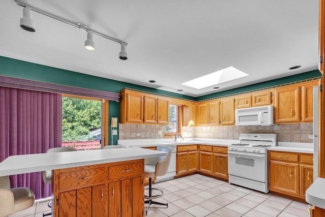 11254 S Whipple St, Chicago, IL 60655 - kitchen featuring white appliances, a skylight, a kitchen bar, light countertops, and tasteful backsplash
