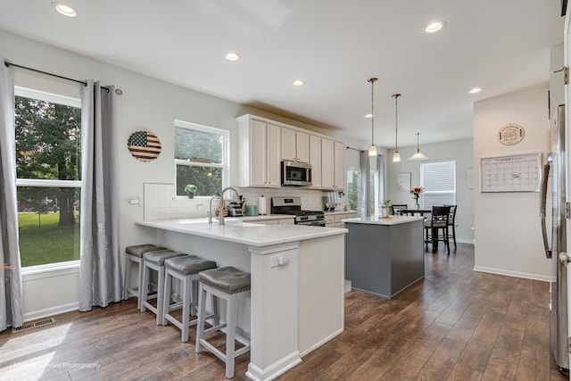 26065 S White Oak Trl, Channahon, IL 60410 - kitchen featuring appliances with stainless steel finishes, a center island, dark wood-style flooring, backsplash, and recessed lighting