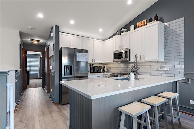 2447 Saddle Ridge Dr, Joliet, IL 60432 - kitchen with stainless steel appliances, decorative backsplash, a peninsula, light wood-type flooring, and a kitchen bar