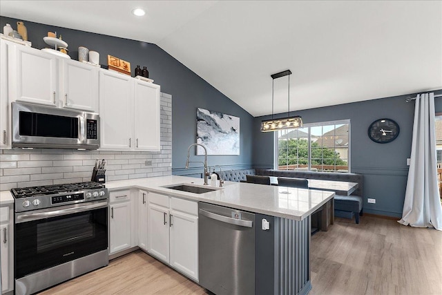 2447 Saddle Ridge Dr, Joliet, IL 60432 - kitchen featuring stainless steel appliances, light wood-type flooring, lofted ceiling, a peninsula, and white cabinets