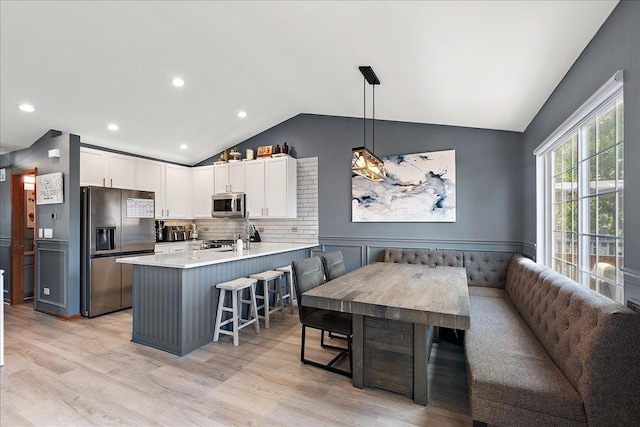 2447 Saddle Ridge Dr, Joliet, IL 60432 - kitchen featuring stainless steel appliances, lofted ceiling, a peninsula, white cabinets, and light wood-type flooring
