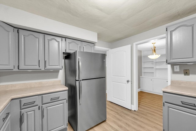 724 Dover Pl, Champaign, IL 61820 - kitchen with freestanding refrigerator, gray cabinetry, light wood-type flooring, light countertops, and a textured ceiling