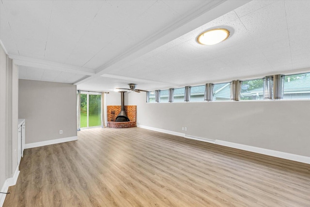 724 Dover Pl, Champaign, IL 61820 - unfurnished living room with a wood stove, light wood-type flooring, plenty of natural light, and beamed ceiling