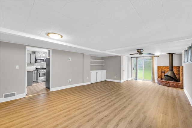 724 Dover Pl, Champaign, IL 61820 - unfurnished living room with a wood stove, light wood-style flooring, and a ceiling fan