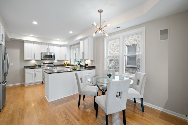 1242 W Ohio St Unit 2E, Chicago, IL 60642 - kitchen with appliances with stainless steel finishes, a chandelier, light wood finished floors, white cabinetry, and recessed lighting