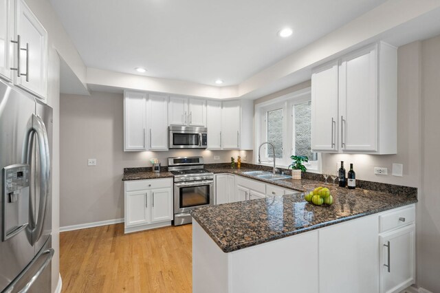 1242 W Ohio St Unit 2E, Chicago, IL 60642 - kitchen featuring stainless steel appliances, white cabinets, dark stone countertops, a peninsula, and light wood-style floors