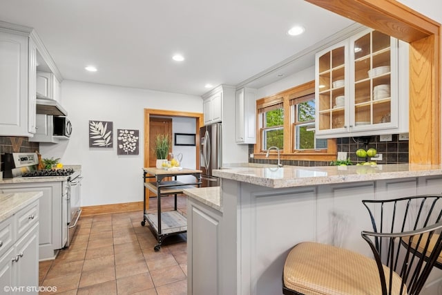 128 Coolidge Ave, Barrington, IL 60010 - kitchen with appliances with stainless steel finishes, glass insert cabinets, a peninsula, tasteful backsplash, and white cabinetry