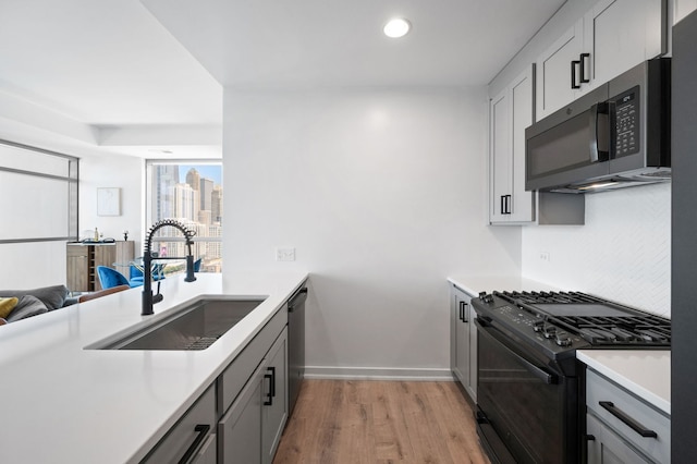303 W Ohio St Unit 2302, Chicago, IL 60654 - kitchen with black range with gas stovetop, stainless steel dishwasher, light countertops, light wood finished floors, and gray cabinetry