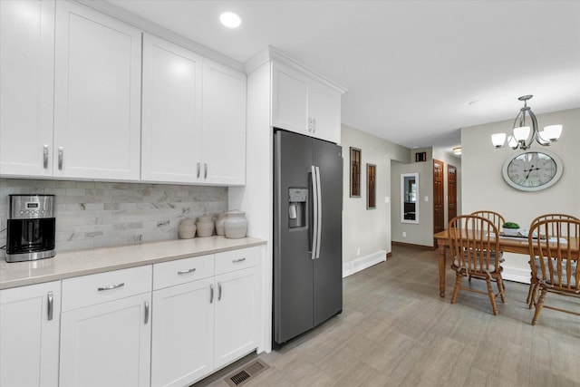 20 Park Dr, Villa Grove, IL 61956 - kitchen featuring stainless steel fridge, decorative backsplash, light countertops, a chandelier, and white cabinetry