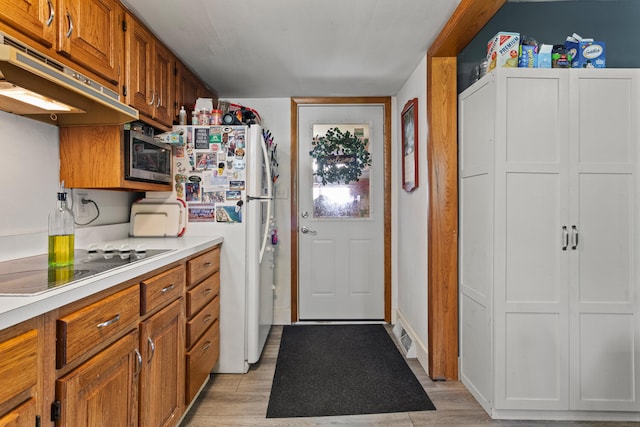 2070 County Road 2400, Thomasboro, IL 61878 - kitchen with stainless steel microwave, black electric cooktop, under cabinet range hood, light countertops, and brown cabinetry