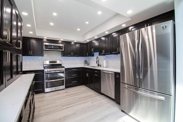 15705 Lake Hills Ct Unit 2N, Orland Park, IL 60462 - kitchen with stainless steel appliances, dark cabinets, light stone counters, a tray ceiling, and tasteful backsplash