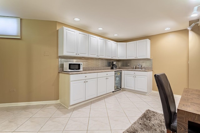 711 E Greenview Rd, Itasca, IL 60143 - kitchen featuring wine cooler, decorative backsplash, white microwave, white cabinets, and light tile patterned flooring