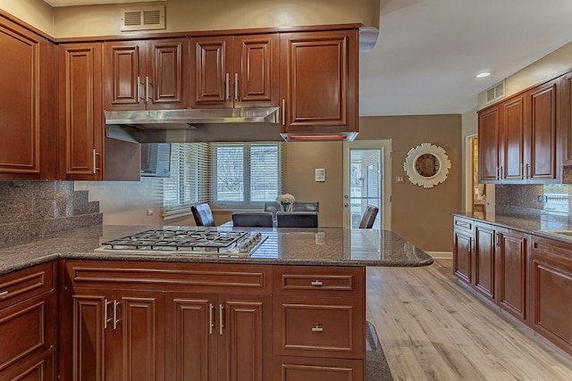 711 E Greenview Rd, Itasca, IL 60143 - kitchen featuring stainless steel gas stovetop, tasteful backsplash, light wood finished floors, dark stone counters, and under cabinet range hood