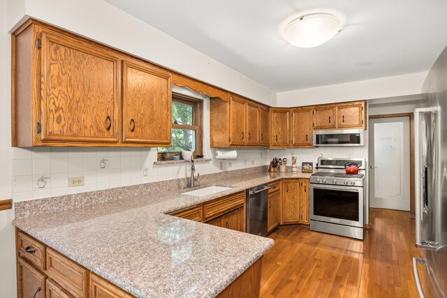 13542 S Erin Dr, Homer Glen, IL 60491 - kitchen with stainless steel appliances, brown cabinetry, a peninsula, wood finished floors, and backsplash