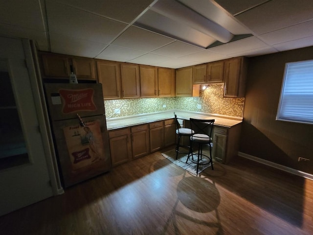 310 Partridge Ln, Wheeling, IL 60090 - kitchen with freestanding refrigerator, dark wood-style floors, a paneled ceiling, tasteful backsplash, and brown cabinets