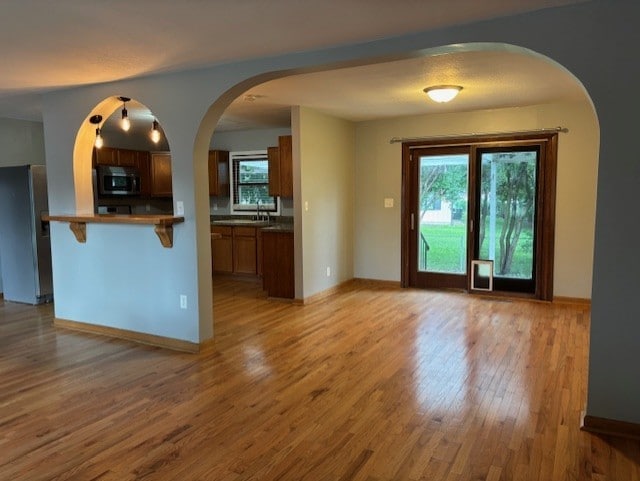 1038 Ruth Crane Dr, Rantoul, IL 61866 - kitchen featuring stainless steel fridge with ice dispenser, light wood-style floors, a kitchen breakfast bar, arched walkways, and brown cabinetry