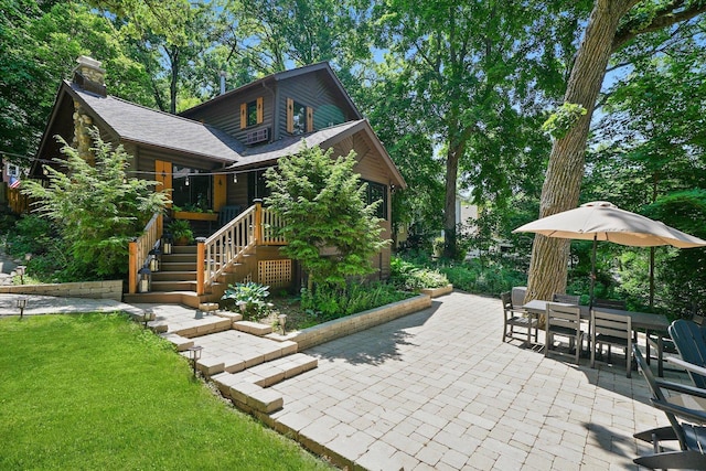 3720 E Lake Shore Dr, Wonder Lake, IL 60097 - view of front of property featuring a patio area, a front lawn, a chimney, outdoor dining area, and stairway