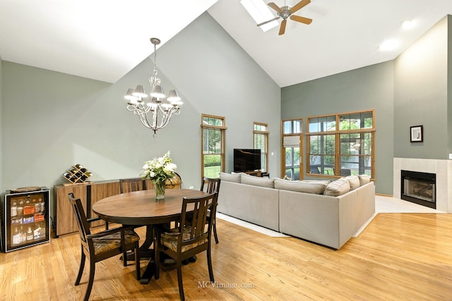 21730 Higley Ln, Frankfort, IL 60423 - dining room featuring high vaulted ceiling, light wood-style flooring, a chandelier, a tiled fireplace, and beverage cooler