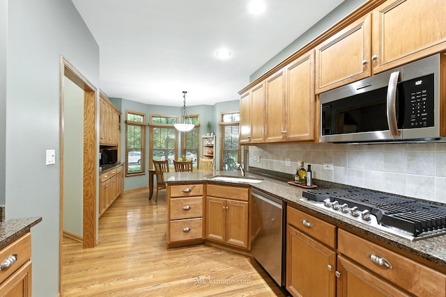 21730 Higley Ln, Frankfort, IL 60423 - kitchen featuring appliances with stainless steel finishes, light wood-style floors, tasteful backsplash, a peninsula, and dark stone counters