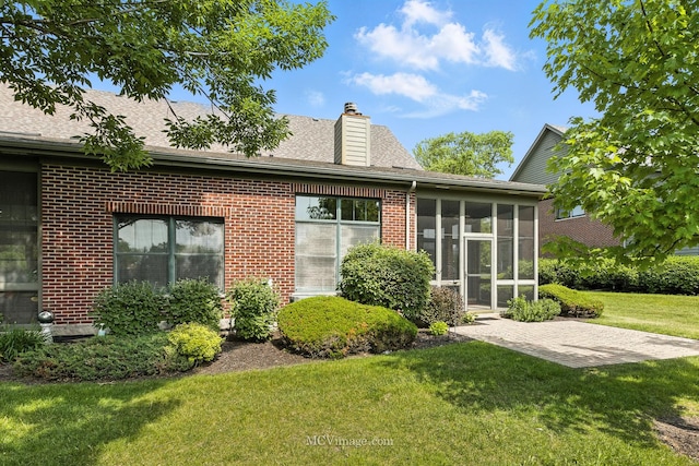 21730 Higley Ln, Frankfort, IL 60423 - rear view of house with a lawn, a chimney, brick siding, a sunroom, and roof with shingles