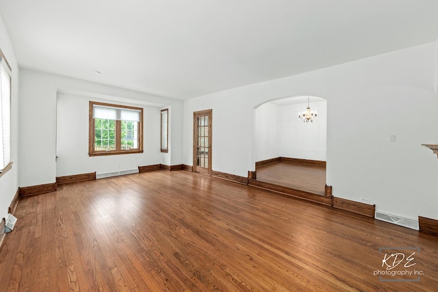 330 S Maple St, Itasca, IL 60143 - spare room featuring baseboard heating, arched walkways, wood finished floors, and a chandelier