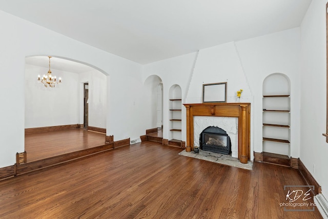 330 S Maple St, Itasca, IL 60143 - unfurnished living room with built in features, wood finished floors, a fireplace, baseboard heating, and a chandelier