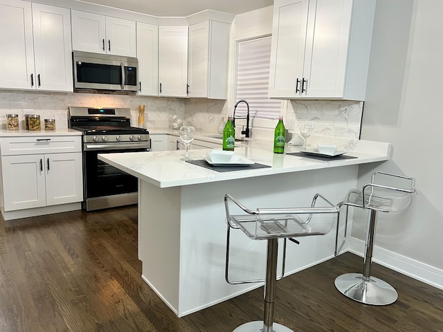 12837 S Aberdeen St, Calumet Park, IL 60827 - kitchen with stainless steel appliances, a kitchen breakfast bar, dark wood-type flooring, light countertops, and white cabinetry