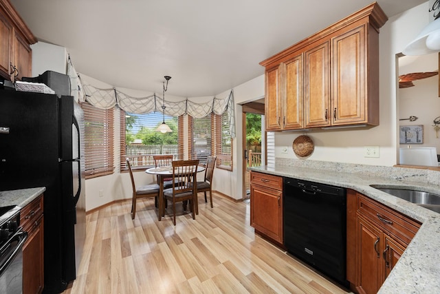 937 Wellington Cir, Aurora, IL 60506 - kitchen with black appliances, brown cabinets, light wood finished floors, light stone counters, and hanging light fixtures