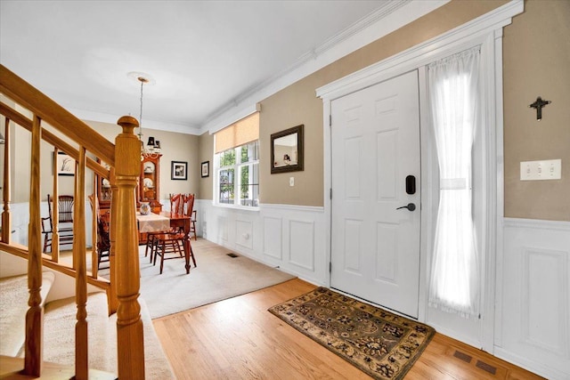 2420 Columbia Ln, Montgomery, IL 60538 - foyer with a wainscoted wall, stairway, light wood-style flooring, crown molding, and a chandelier