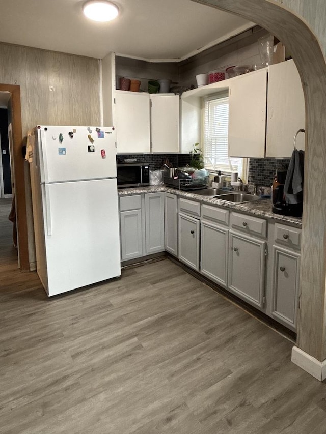1221 Nicholson St, Joliet, IL 60435 - kitchen featuring freestanding refrigerator, stainless steel microwave, light wood-type flooring, arched walkways, and tasteful backsplash