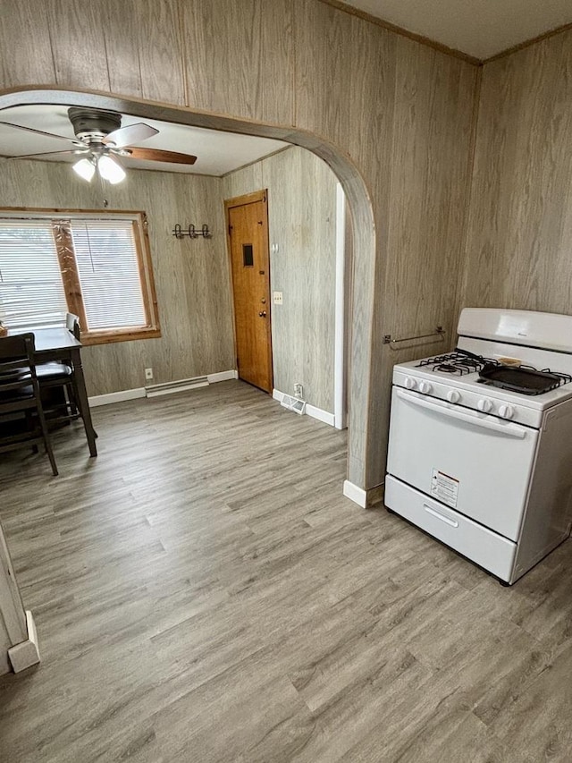 1221 Nicholson St, Joliet, IL 60435 - kitchen with white gas range, arched walkways, ceiling fan, wood walls, and light wood-style floors