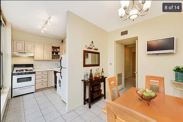 3200 N Lake Shore Dr Unit 1709, Chicago, IL 60657 - kitchen with white gas range oven, under cabinet range hood, a chandelier, cream cabinets, and light tile patterned floors