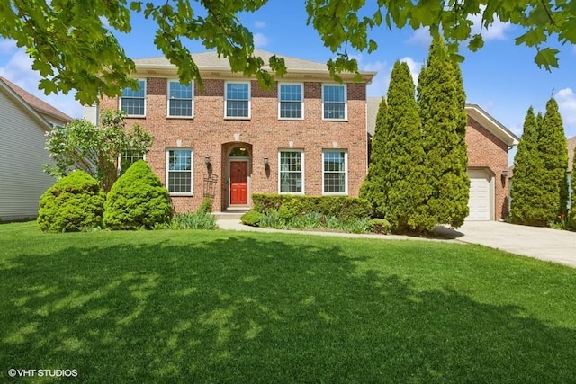 387 Essex Dr, Oswego, IL 60543 - colonial house with a front yard, concrete driveway, brick siding, and a garage