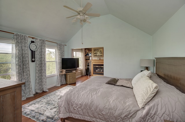 387 Essex Dr, Oswego, IL 60543 - bedroom with wood finished floors, a glass covered fireplace, high vaulted ceiling, and ceiling fan