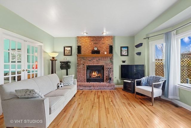 387 Essex Dr, Oswego, IL 60543 - living room with light wood-style floors, french doors, a brick fireplace, and plenty of natural light