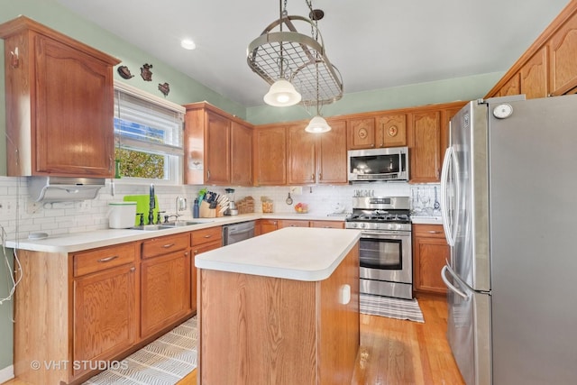 387 Essex Dr, Oswego, IL 60543 - kitchen with appliances with stainless steel finishes, a kitchen island, light countertops, backsplash, and light wood-style flooring