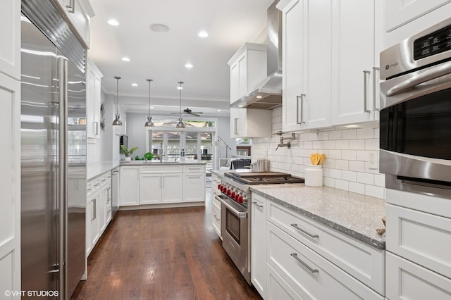 3715 N Wayne Ave, Chicago, IL 60613 - kitchen featuring high end appliances, wall chimney range hood, backsplash, ornamental molding, and white cabinetry