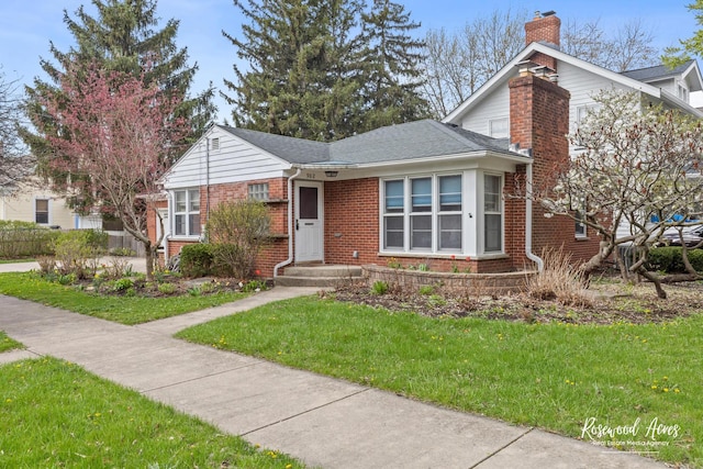 902 W Downer Pl, Aurora, IL 60506 - bungalow with brick siding, a chimney, a front lawn, and a shingled roof