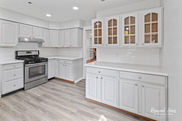 902 W Downer Pl, Aurora, IL 60506 - kitchen with gas stove, under cabinet range hood, glass insert cabinets, decorative backsplash, and recessed lighting