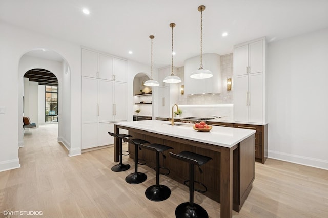 838 N Damen Ave Unit 1, Chicago, IL 60622 - kitchen featuring light wood-style flooring, arched walkways, light countertops, a kitchen island with sink, and a kitchen breakfast bar