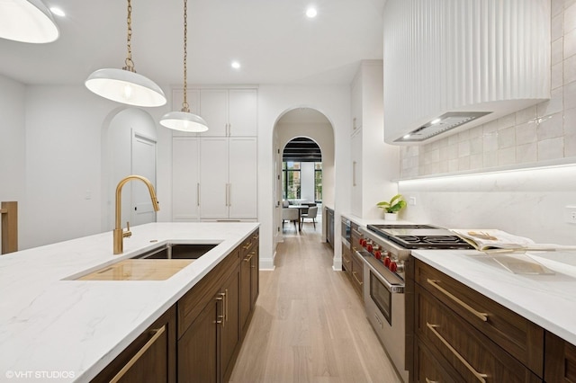 838 N Damen Ave Unit 1, Chicago, IL 60622 - kitchen featuring stainless steel stove, arched walkways, light wood-type flooring, decorative backsplash, and hanging light fixtures