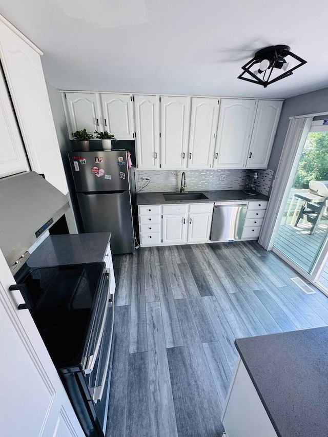 530 Cottonwood Cir, Bolingbrook, IL 60440 - kitchen featuring stainless steel appliances, white cabinetry, dark wood finished floors, decorative backsplash, and dark countertops