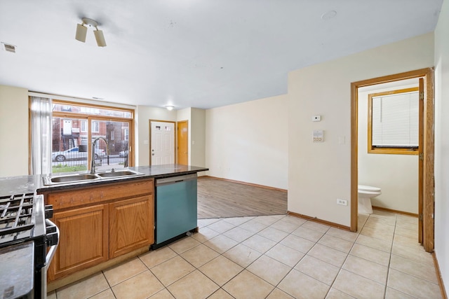 2716 W Polk St, Chicago, IL 60612 - kitchen with dishwashing machine, stainless steel range with gas cooktop, dark countertops, light tile patterned floors, and brown cabinetry