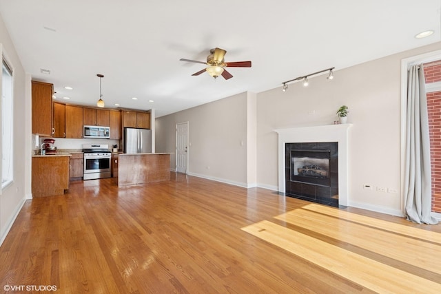 6123 S Kimbark Ave Unit 2N, Chicago, IL 60637 - unfurnished living room with ceiling fan, a tiled fireplace, recessed lighting, light wood-style flooring, and rail lighting