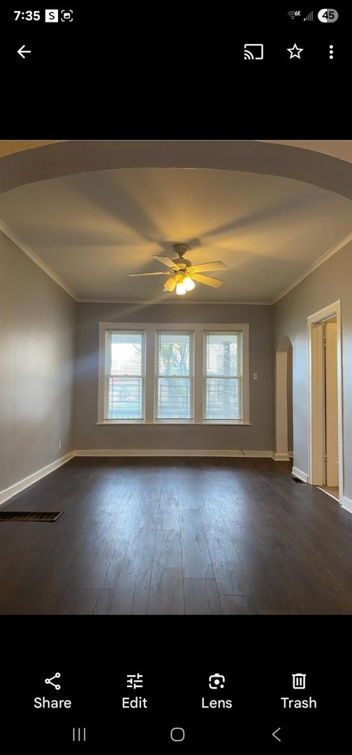 spare room with crown molding, arched walkways, dark wood-style flooring, and ceiling fan
