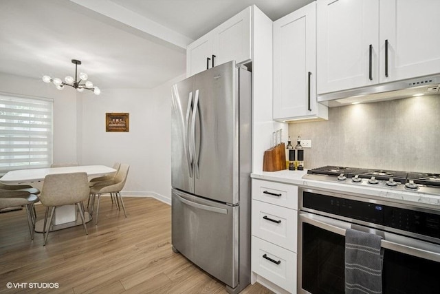 975 W Happfield Dr, Arlington Heights, IL 60004 - kitchen featuring appliances with stainless steel finishes, under cabinet range hood, a chandelier, light countertops, and white cabinetry