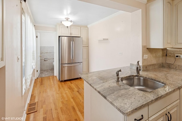 3837 Kirk St, Skokie, IL 60076 - kitchen featuring freestanding refrigerator, crown molding, light wood-type flooring, cream cabinetry, and a peninsula