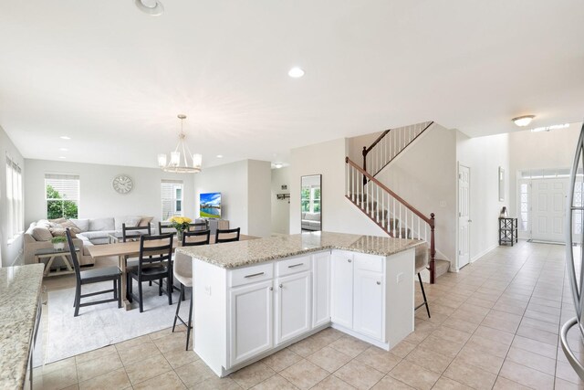 9054 Clinnin Ln, Huntley, IL 60142 - kitchen featuring light tile patterned flooring, a chandelier, open floor plan, a kitchen breakfast bar, and white cabinetry